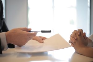 un hombre con traje le está entregando un papel a una mujer.